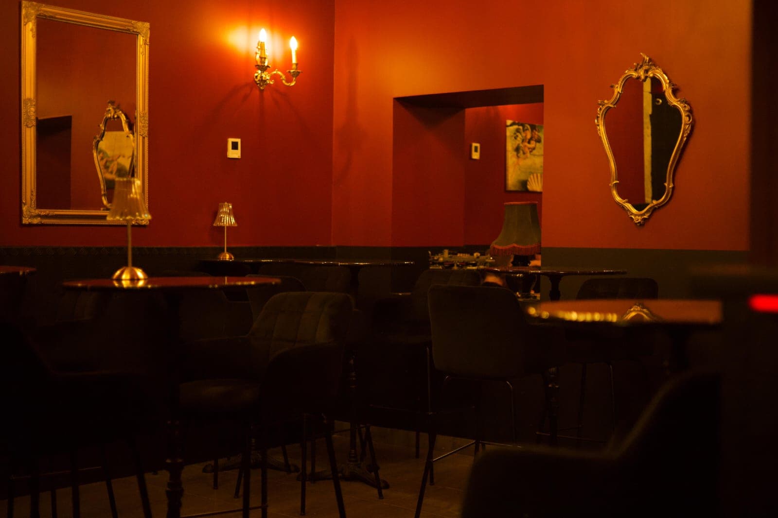 Salle du Bluebird : banquettes sombres, tables rondes, miroirs dorés et murs rouges