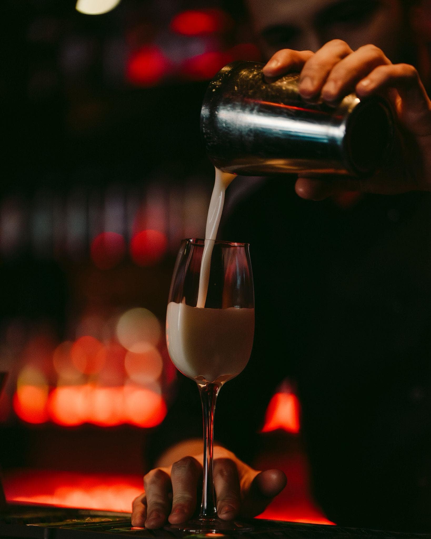 Barman versant un cocktail crémeux du shaker dans une flûte